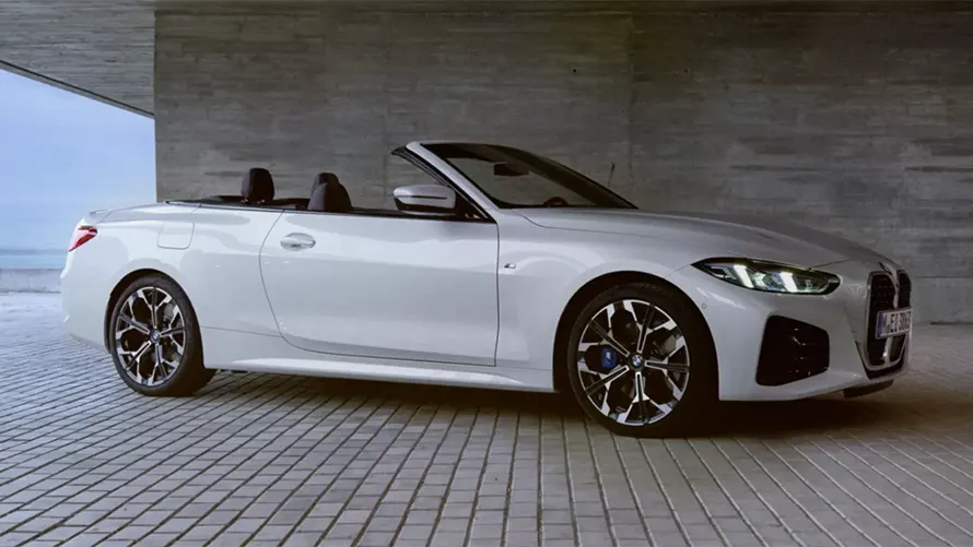 Weißes BMW 4er Cabrio steht ohne Insassen in moderner, überdachter Umgebung auf Pflastersteinen.