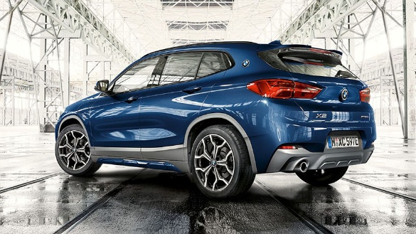 Blauer BMW X2 in einem modernen, lichtdurchfluteten Ausstellungsraum, von der Seite fotografiert.
