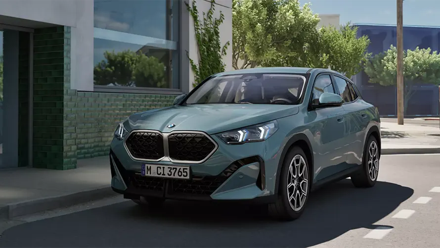 Blauer BMW X2 steht auf einer Straße vor einem modernen Gebäude und Bäumen im Hintergrund.