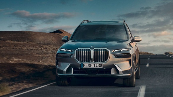 BMW X7 in Bewegung auf einer Straße in einer kargen Landschaft bei bewölktem Himmel.