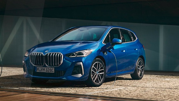 Blauer BMW Hybridwagen an Ladestation auf gepflastertem Boden.