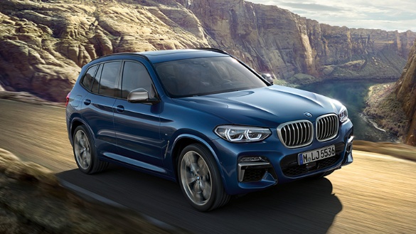 Blauer BMW X3 fährt auf einer Straße durch eine felsige Landschaft bei Tageslicht.
