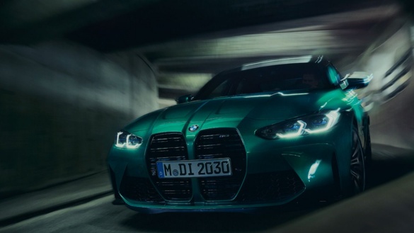 Grüner BMW in einem Tunnel, Frontansicht, mit eingeschaltetem Licht.