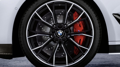 BMW-Rad mit Doppelspeichen-Design und roter Bremse vor weißem Fahrzeughintergrund.