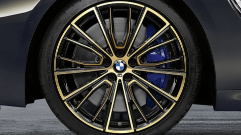 Nahaufnahme eines gold-schwarzen BMW M-Rades mit Vielspeichen-Design auf Asphalt.