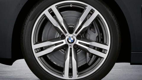 BMW-Leichtmetallrad mit Doppelspeichen-Design, silbern, vor grauem Hintergrund.