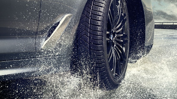 BMW-Auto fährt durch Wasser, Nahaufnahme des Reifens, spritzendes Wasser.