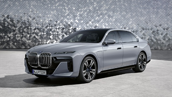 Silberne BMW-Limousine vor einer gemusterten Wand auf grauem Boden.