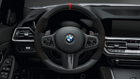 BMW-Lenkrad in einem modernen Fahrzeug-Innenraum, dunkles Design mit roten Akzenten.