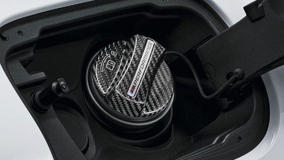 Nahaufnahme einer Kohlefaser-Verschlusskappe mit "M Performance"-Logo in einem Auto.