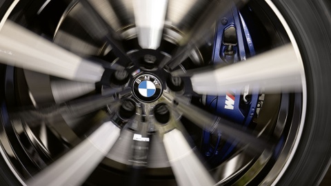 Nahaufnahme eines rotierenden BMW-Rades mit sichtbarem Emblem und blauem Bremssattel.