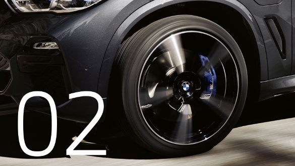 Nahaufnahme eines sich drehenden BMW-Autoreifens mit blauer Bremszange, Zahl 02 sichtbar.