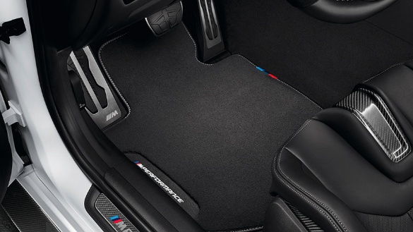 Schwarze BMW Fußmatte im Innenraum eines Autos mit sportlichen Pedalen und Sitzbezügen.