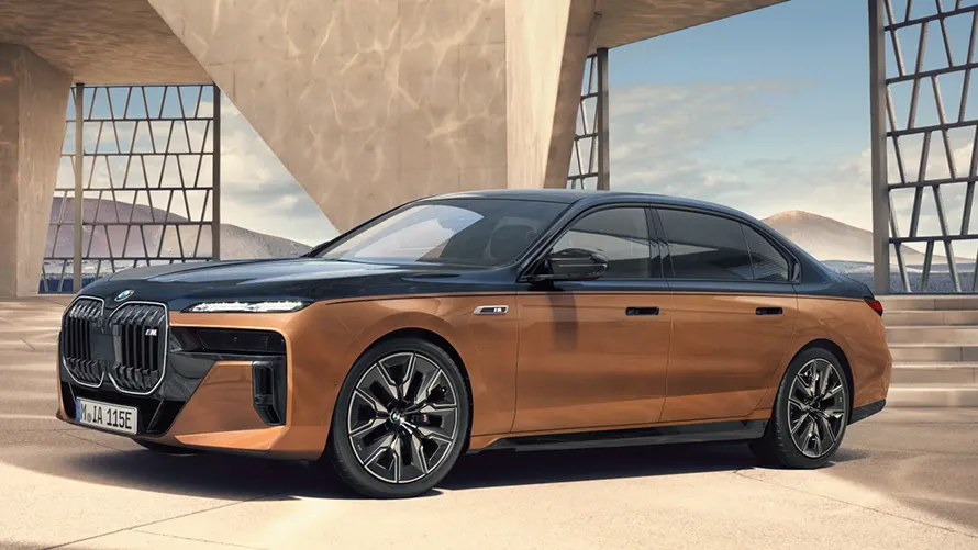 BMW i7 M70 in Bronze und Schwarz, geparkt vor moderner Architektur.