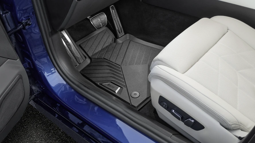 Fußmatte und helles Autositzpolster im Innenraum eines blauen BMWs.