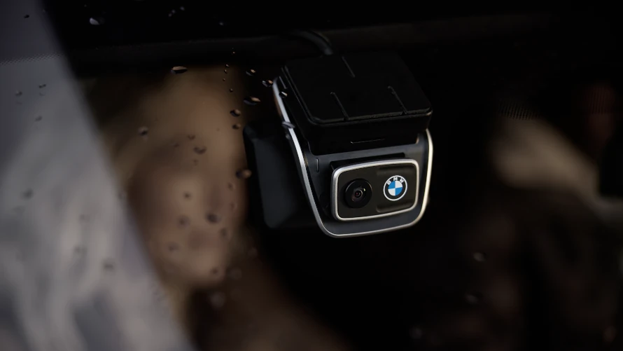 Nahaufnahme einer BMW-Kamera an einer Windschutzscheibe mit Wassertropfen.