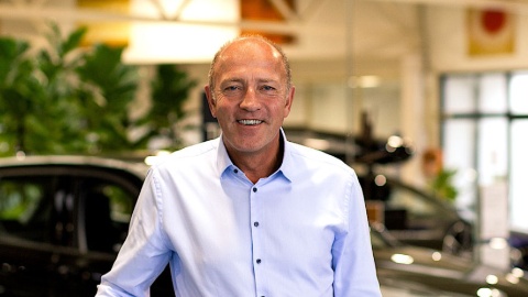 Ein Mann in einem Autohaus mit Pflanzen im Hintergrund.