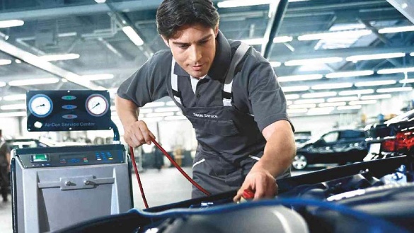 Ein Mechaniker wartet in einer Werkstatt ein Auto-Klimaanlagensystem.