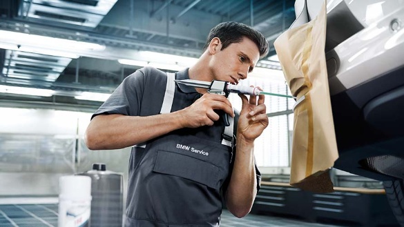 Ein Mechaniker repariert eine Autostoßstange in einer Werkstatt.
